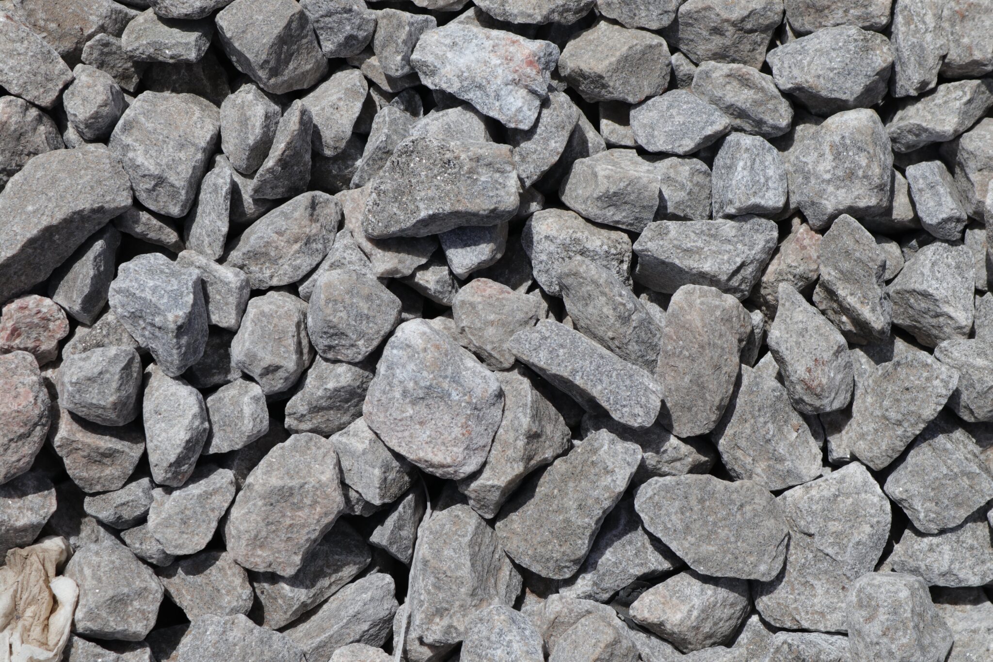 Detailed view of a sunlit pile of rough gray stones. Ideal for textured backgrounds.